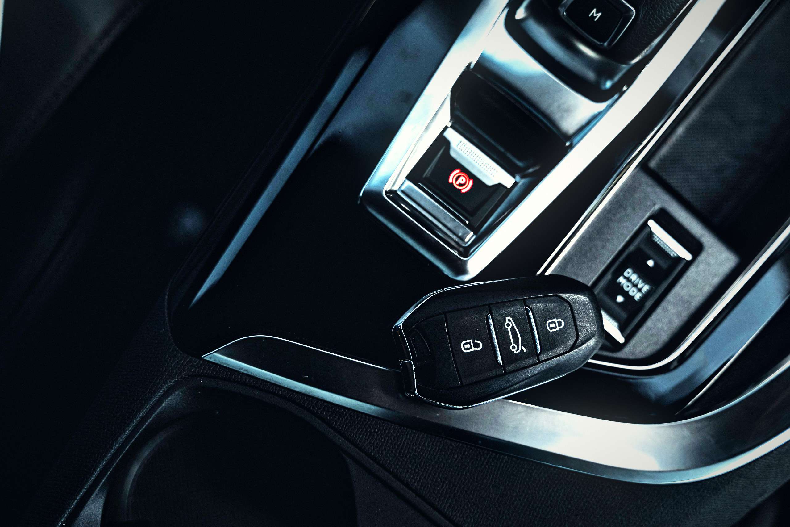 Close-up of a car remote key fob and electronic handbrake in a modern vehicle interior