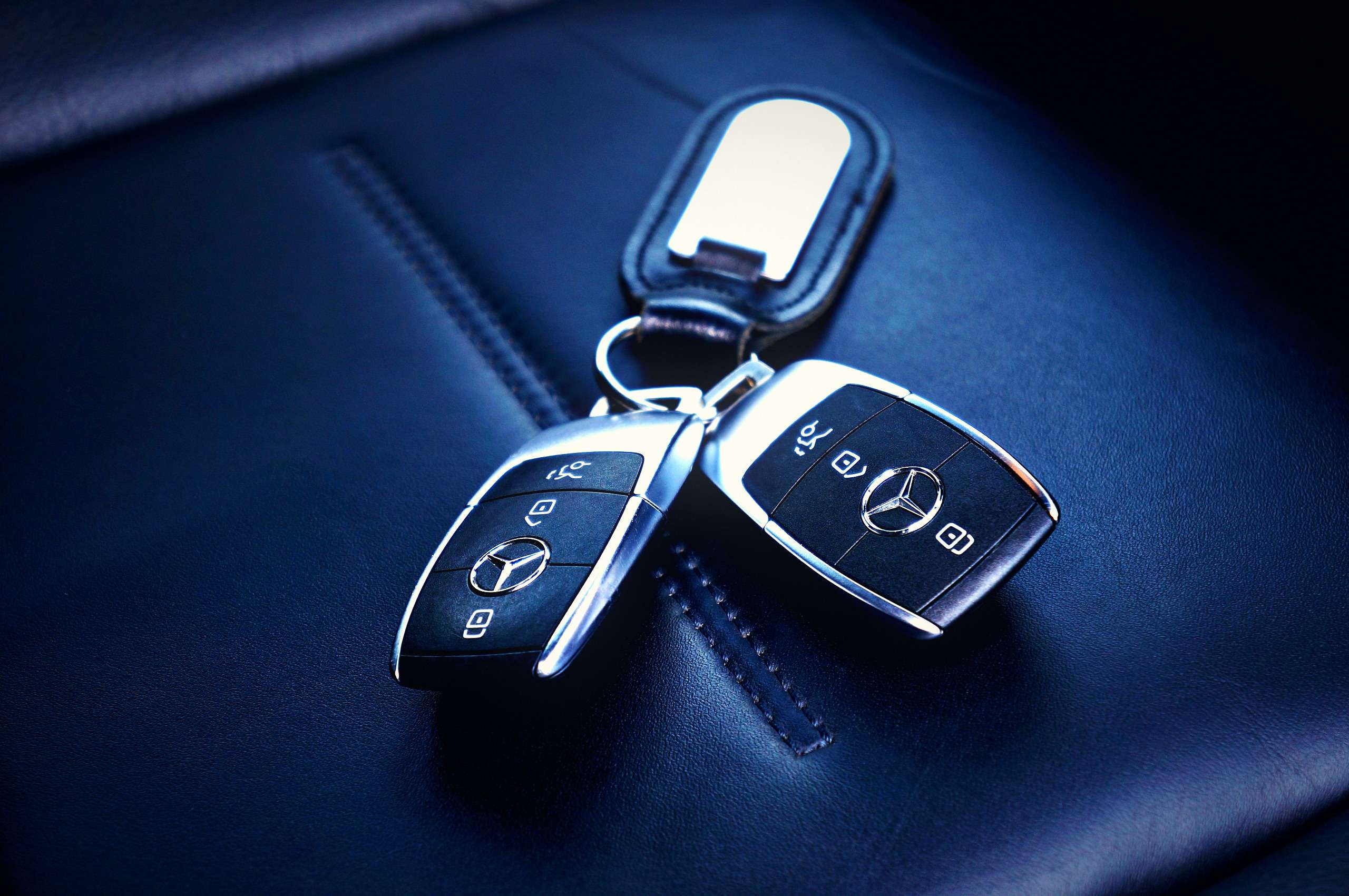 Two matching car key fobs resting together on a car seat