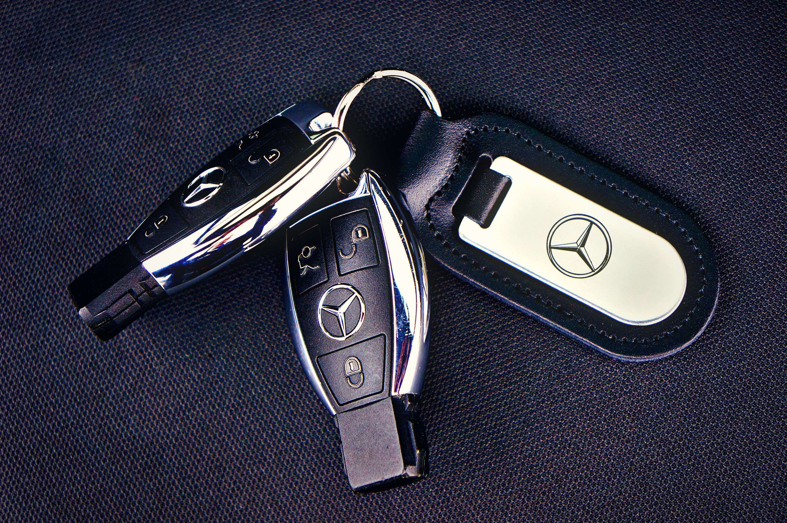 Two Mercedes-Benz car key fobs with a leather keychain, side by side
