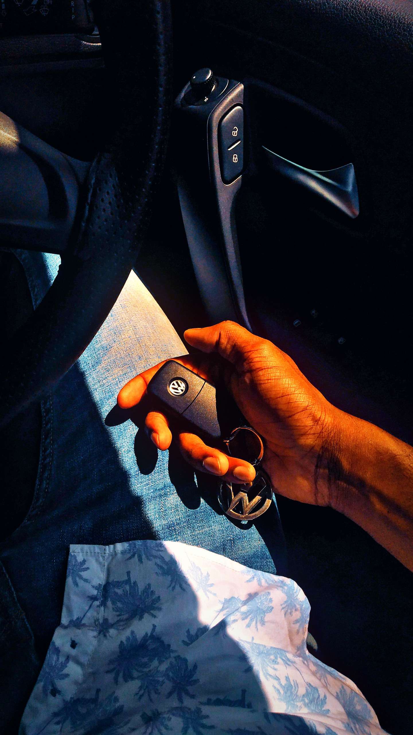 Hand holding a Volkswagen car key fob inside a vehicle