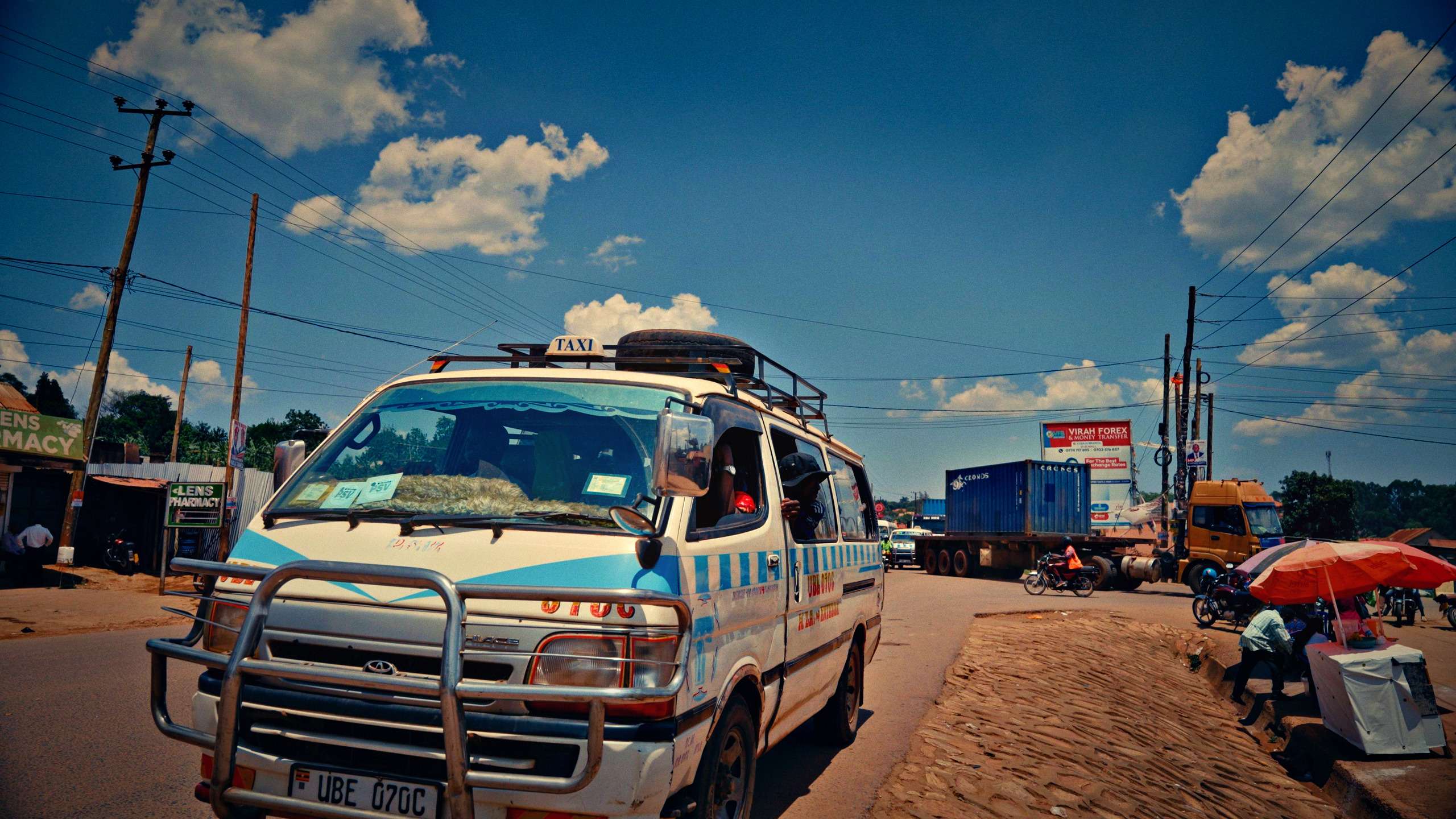 White Toyota Hiace taxi van with a Ugandan number plate on a busy street in Uganda