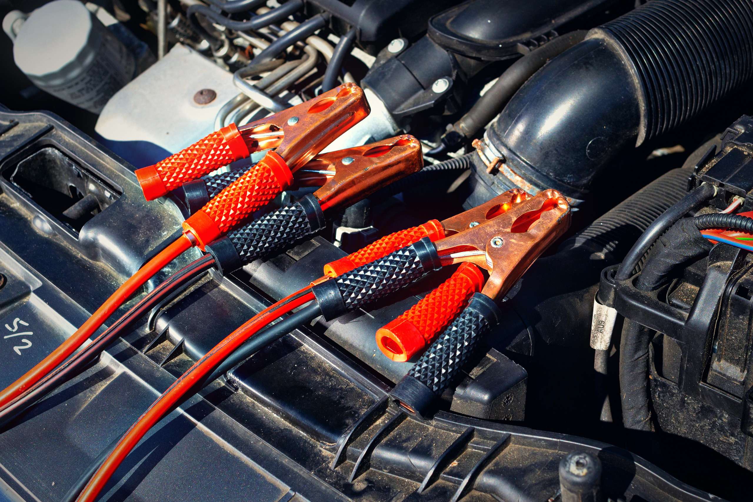 Close-up of a car engine with jump starter cables attached