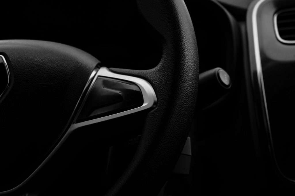 Dark close-up of a car steering wheel and dashboard