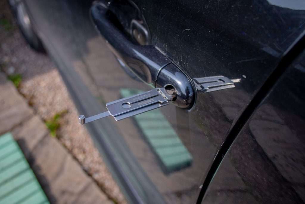 Locksmith tool inserted into a car door lock cylinder during key service